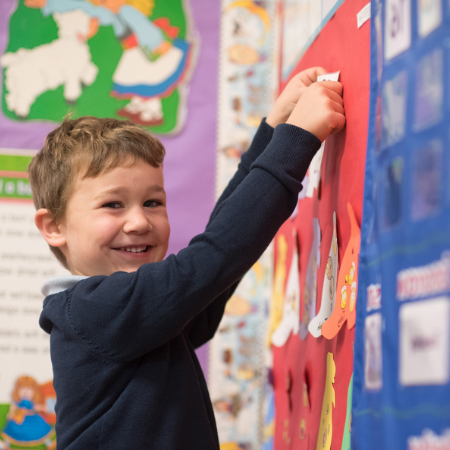 A Dayspring Christian Academy student pinning a paper to a poster board.